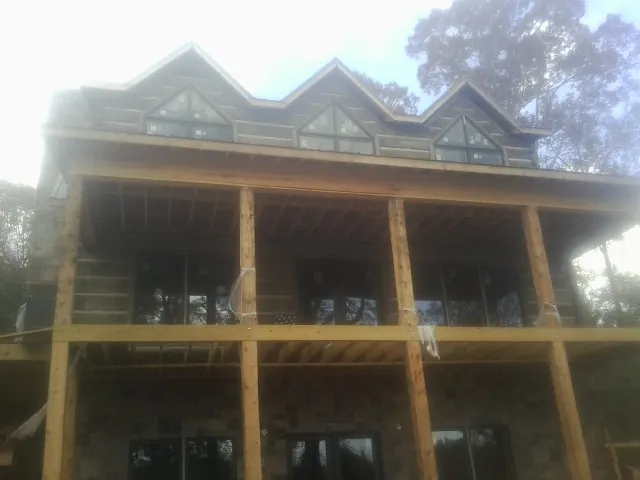 Dormers and porch framing on a large log home under construction — Roof Coating work by our crew in Custer